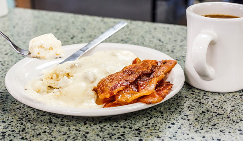 Biscuits and gravy with bacon and a cup of coffee